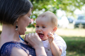 Un enfant jouant dans les bras de sa mère pendant le vin d'honneur - photographe de mariage Ile-de-France