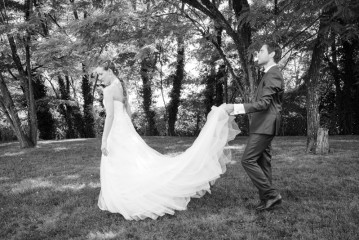Le marié tient la traine de la robe de la mariée pendant une séance photo de couple