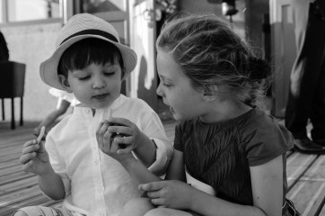 Deux enfants pendant un mariage se partagent une frite au moment du vin d'honneur - photographe de mariage Ile-de-France